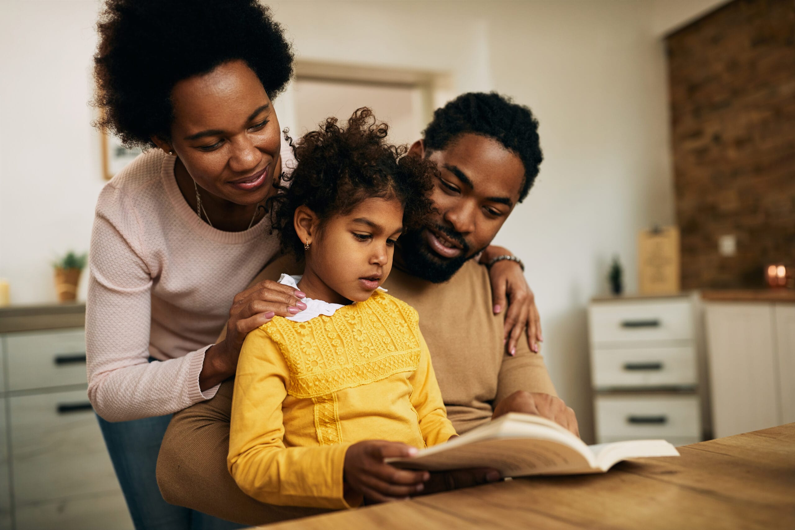 Happy family where parents are supporting child reading book
